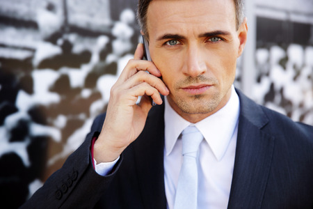 Confident businessman talking on the phone at officeの写真素材