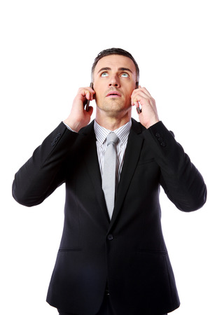 Businessman talking on two cell phones at the same time over white backgroundの写真素材