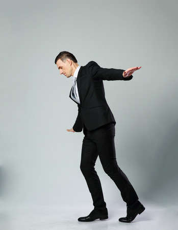 Businessman walking on invisible rope over gray backgroundの写真素材