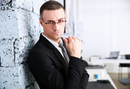 Confident businessman standing near brick wallの写真素材
