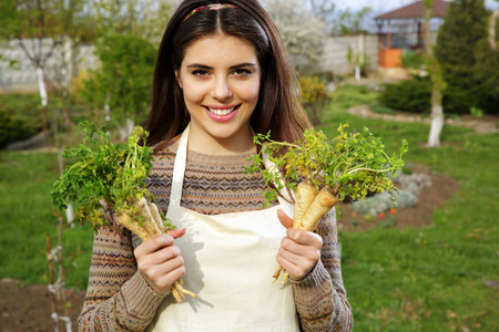 Happy young woman holding fresh vegetables in gardenの写真素材