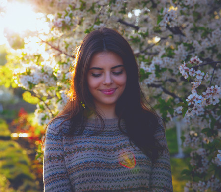 Smiling cute woman standing in spring gardenの写真素材