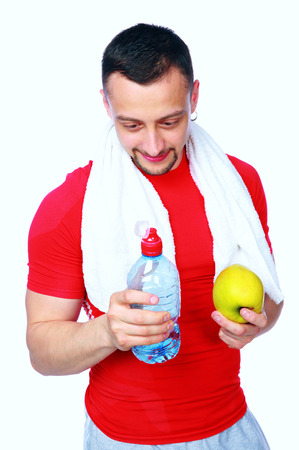 Fitness man just after a workout with water and apple over white backgroundの写真素材