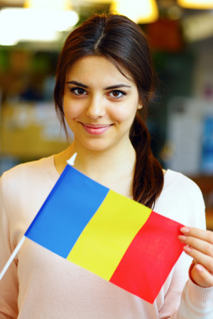 Smiling female student holding flag of Romaniaの写真素材