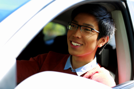 Handsome happy asian man sitting in carの写真素材