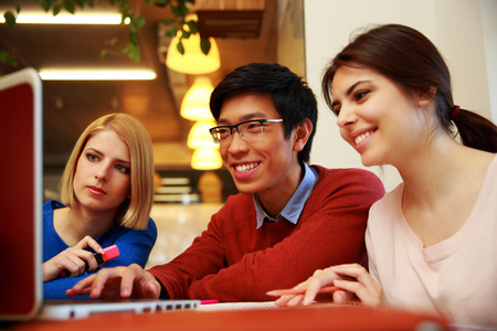 Young smiling friends using laptop 