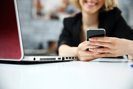 Closeup portrait of a female hands using smartphone in officeの写真素材