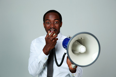 African man shouting through a megaphone on gray backgroundの写真素材