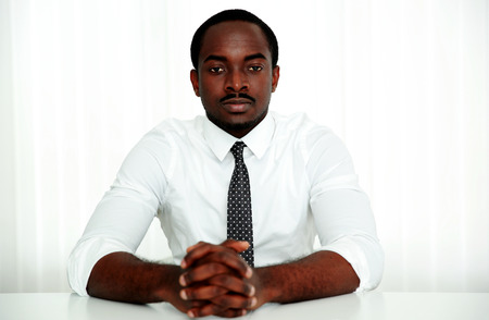 Thoughtful african man sitting at the table in officeの写真素材