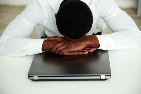 African man sleeping at his workplace in officeの写真素材
