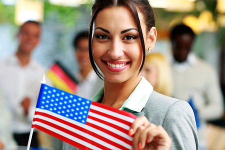 Happy businesswoman holding flag of USA in front of colleaguesの写真素材