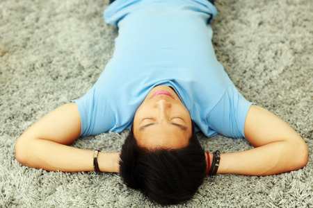 Young asian man sleeping on the carpet at homeの写真素材