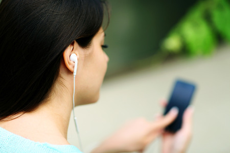 Closeup portrait of a woman in headphones listening to music with her smartphoneの写真素材