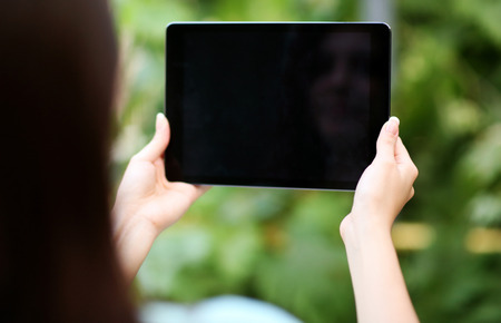 Closeup portrait of a female hands holding tablet computer with blank screenの写真素材