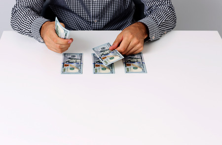 Portrait of businessman counting hundred dollar bills at deskの写真素材