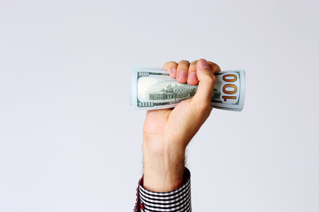 Closeup portrait of a male hand raised up with bill of dollarsの写真素材