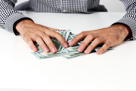 Closeup of a male hands hold dollars on the tableの写真素材