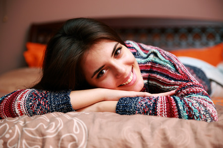 Cheerful attractive woman lying on the bed at home