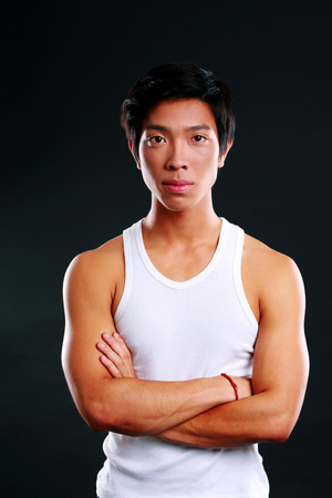 Portrait of a serious asian man with arms folded on black backgroundの写真素材