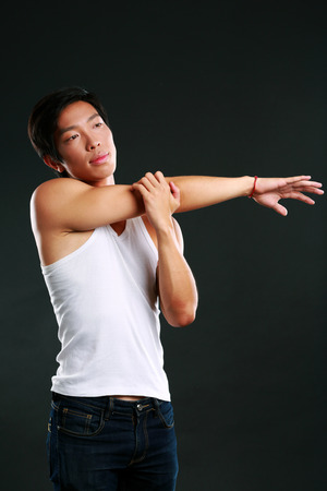 Pensive asian man stretching hands on black backgroundの写真素材