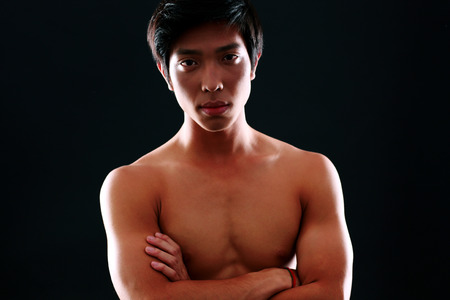 Portrait of a serious asian man with arms folded on black backgroundの写真素材