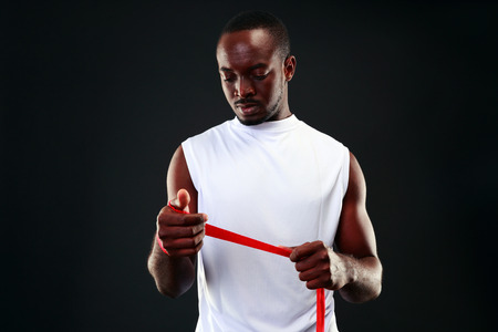 African man with tape measure over black background