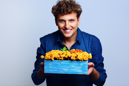 Happy man holding flowers over blue backgroundの写真素材