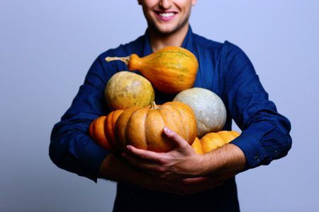 Happy man holding pumpkin over blue backgroundの写真素材