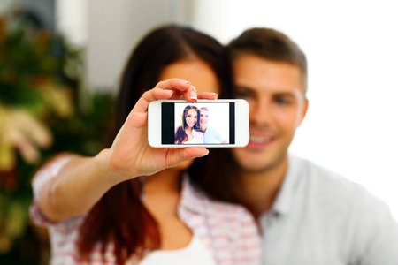 Portrait of a happy couple making selfie photo with smartphone.の写真素材