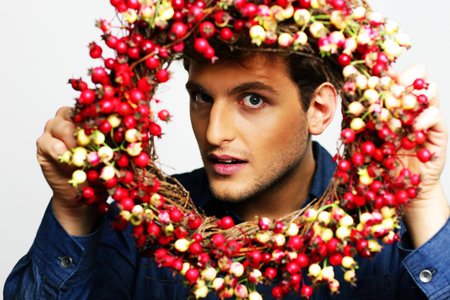 Man looking through a wreath over gray backgroundの写真素材