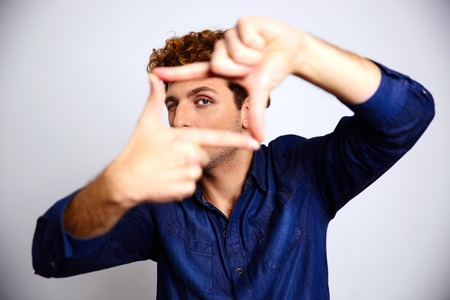 Man framing photograph over gray backgroundの写真素材