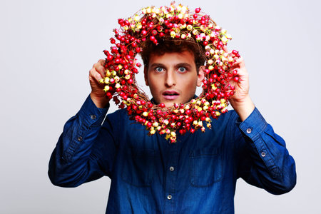 Funny man looking through a wreath over gray backgroundの写真素材