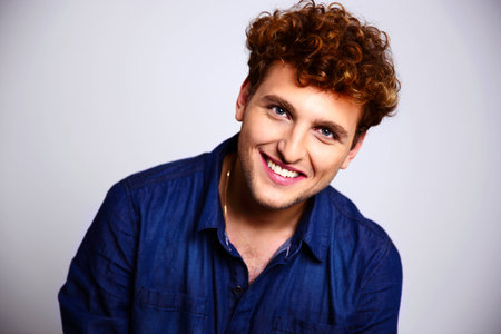 Portrait of a happy man in blue shirt on gray background