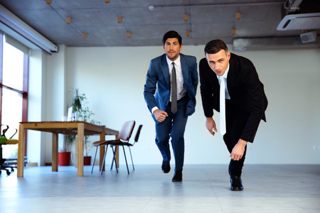 Two businessman running together in office. Business conceptの写真素材