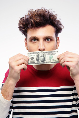 Portrait of a man holding money over gray backgroundの写真素材