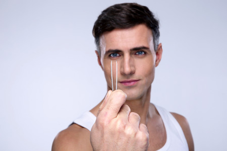 Handsome man holding tweezers. Focus on tweezersの写真素材