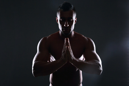 Silhouette of a muscular man prayingの写真素材