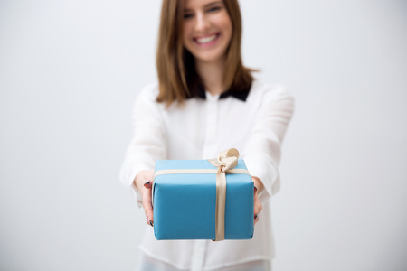 Smiling young woman giving gift. Focus on a giftの写真素材
