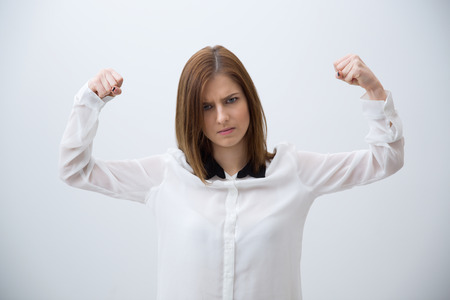 Business woman showing her strength over gray backgroundの写真素材