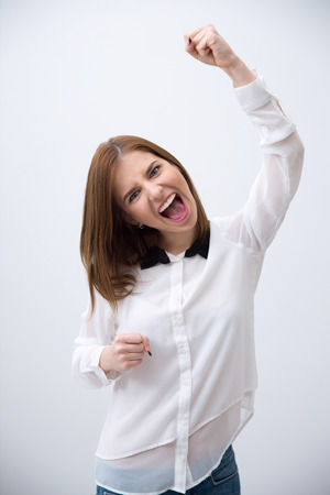 Excited young woman celebrating success over gray backgroundの写真素材
