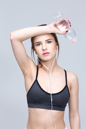 Portrait of a sporty young woman standing over gray backgroundの写真素材