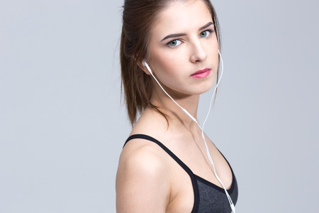 Portrait of a beautiful woman listening music in headphones over gray backgroundの写真素材