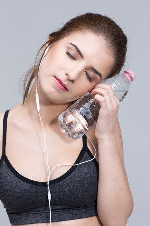 Closeup portrait of a sporty woman with bottle of waterの写真素材