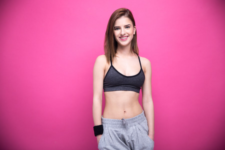 Portrait of a happy sports woman standing over pink backgroundの写真素材