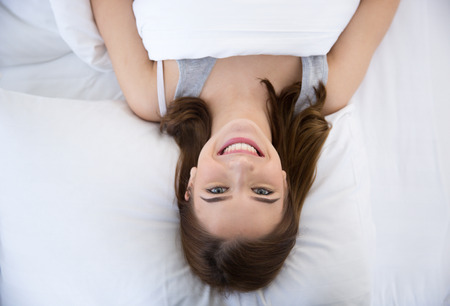Top view portrait of a young cheerful woman lying on the bed