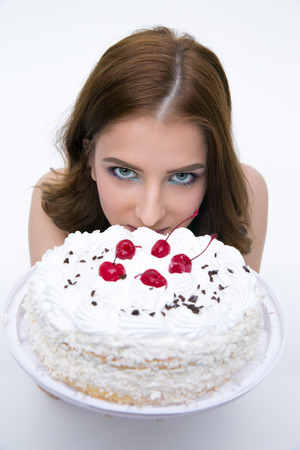 Portrait of a beautiful woman with cake over gray backgroundの写真素材