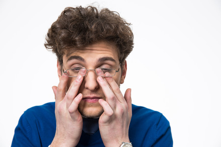 Young businessman rubbing his eyes over white backgroundの写真素材