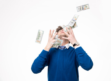 Happy businessman raising hands up and looking up under money rainの写真素材