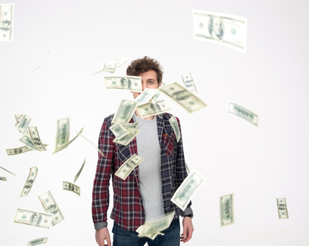 Casual man throwing Money Into Air over gray backgroundの写真素材