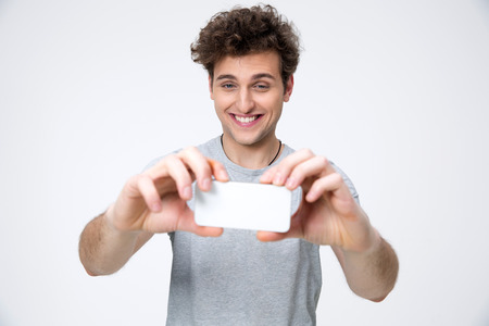 Happy casual man making photo on smartphoneの写真素材